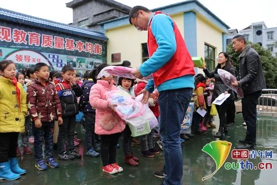 酉阳县山茶花志愿者为留守儿童发放新年心愿礼物。酉阳县团委 供图